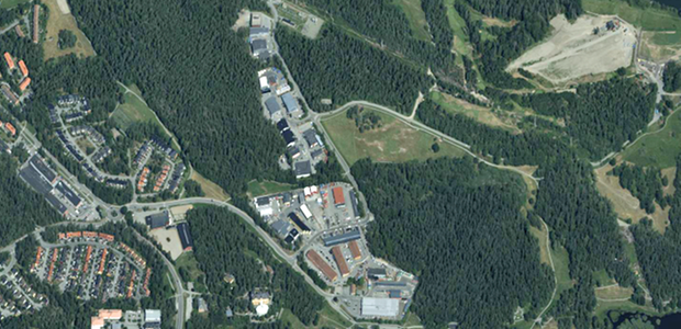 Flygbild över ett skogsområde och ett antal byggnader.