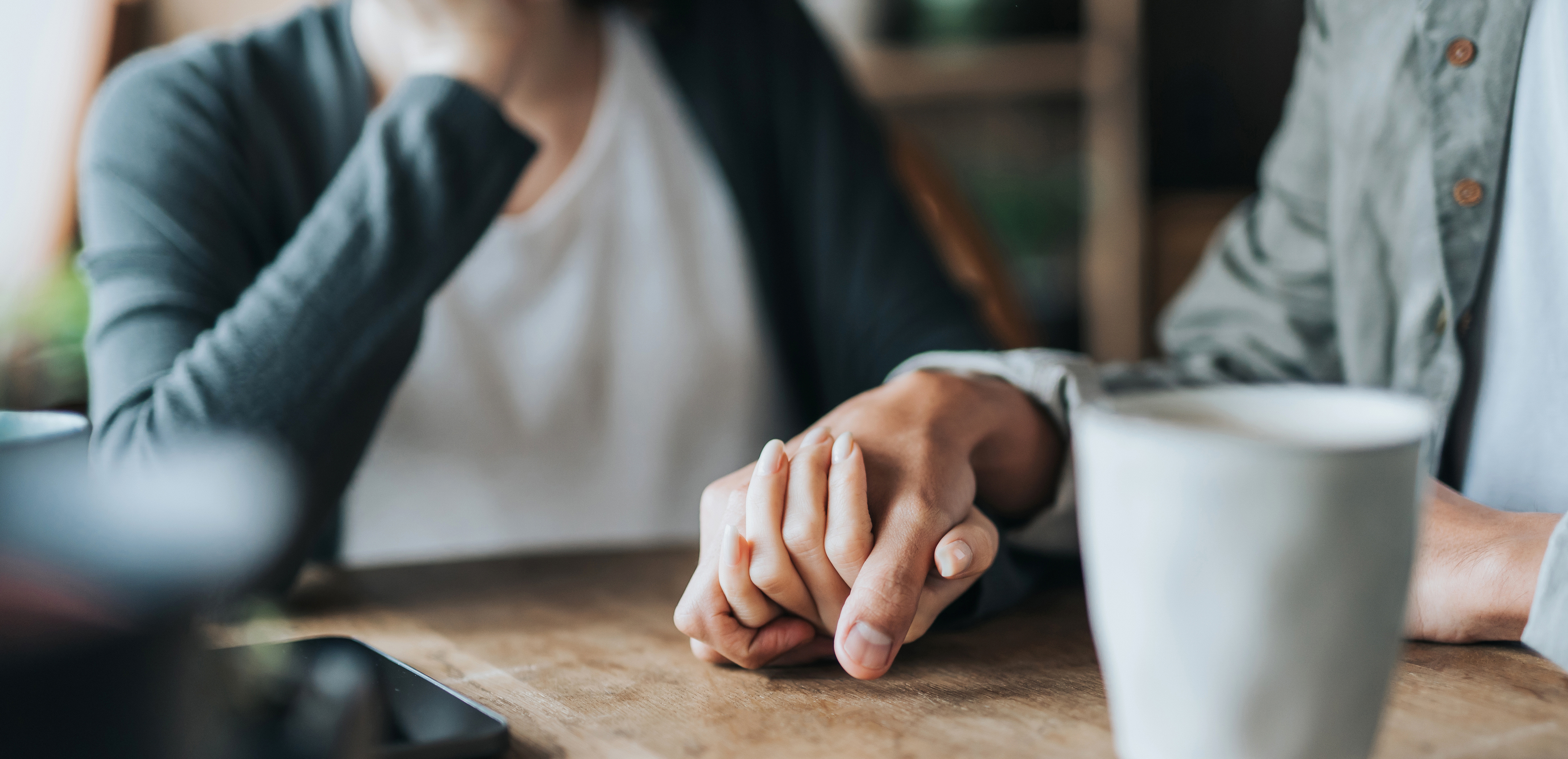 två personers händer och en kaffekopp