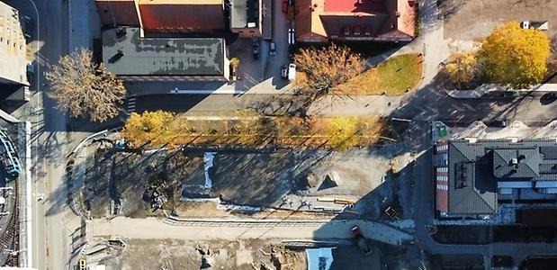 Drönarbild över en byggplats, hus och träd runtom