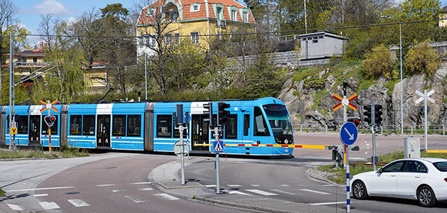Järnvägskorsning med bommar och ett tåg som passerar.
