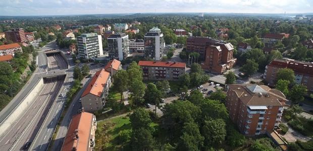 Drönarbild över stor väg med två broar, flerbostadshus vid sidan om vägen.
