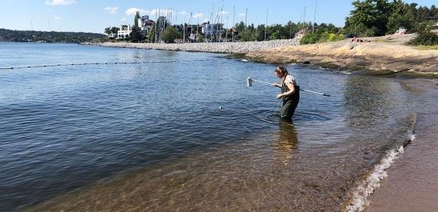 Kvinna vid badstrand som tar vattenprov