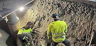 Två varselklädda män (gula) som arbetar i en grusgrop.