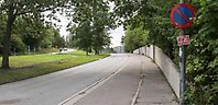Väg med trottoar och cykelbana, träd och trafikmärke p-förbud.