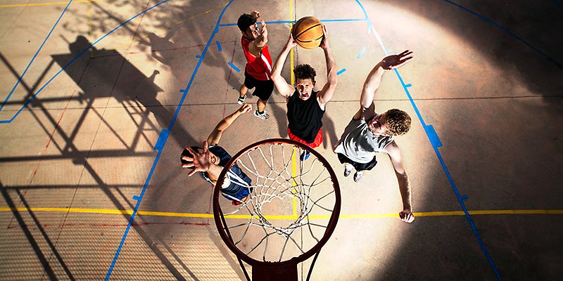 Fyra killar spelar basket. 