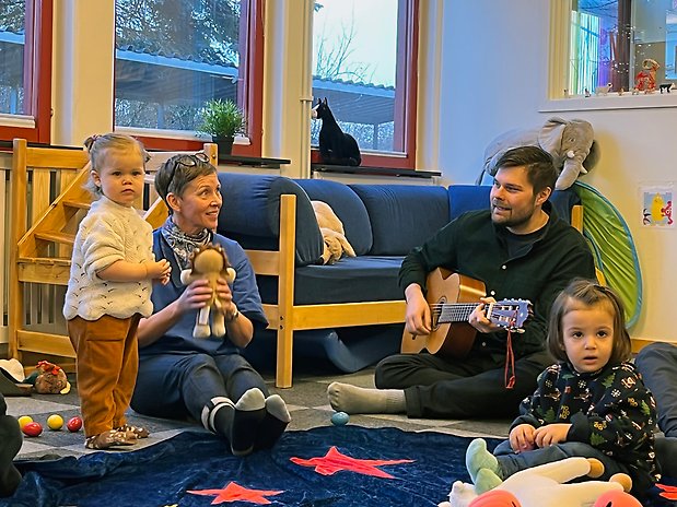 Pappa Erik spelar gitarr, dottern Ella, 16 månader, hänger med. På bild även förskollärare Camilla Persson och besökaren Aysesu, 19 månader.