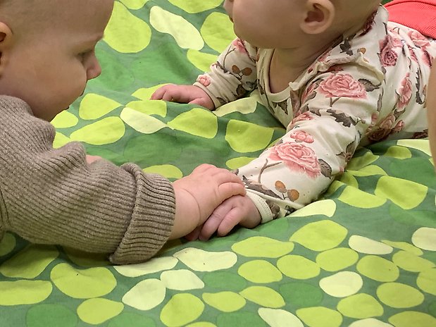 Två av öppna förskolans minsta besökare, Leia och Juni, håller hand.